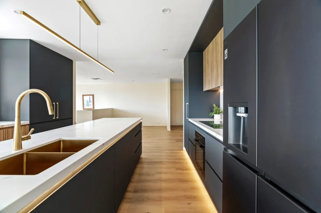 A photo of a luxury kitchen renovation to a home in Canberra showing the cabinetry, stone benchtops, and kitchen sink